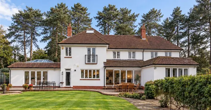 Rear of a white house with an extension and a landscaped lawn